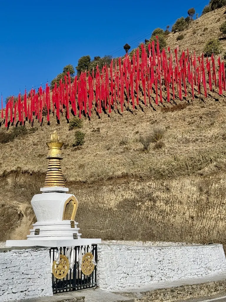 Prayer flags and a chorten on a Bhutanese hillside